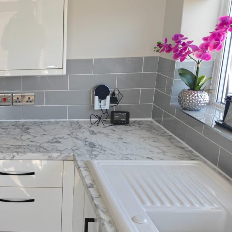 Worktop replacement Modern kitchen countertop with grey tiles, a sink, and a pink orchid in a pot.