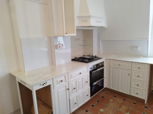 Modern kitchen with white cabinets, gas stove, and tiled floor.