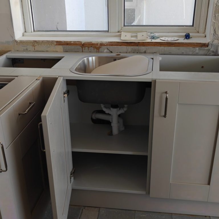 Ready for worktop A partially assembled kitchen unit with an exposed sink and open cupboard doors.