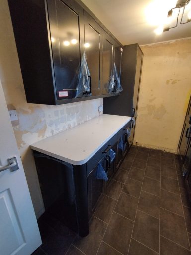 Kitchen with black cabinets, white countertop, and tiled floor.