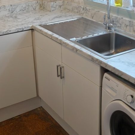 Worktop with sink Modern kitchen corner with a stainless steel sink and washing machine. Marble countertops.