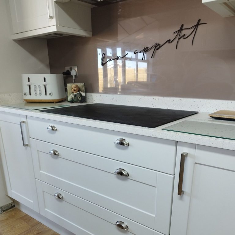 White kitchen Modern kitchen with white cabinets, a black countertop, and a decorative wall.