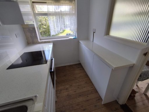 Modern kitchen with white cabinetry, a countertop, and natural light from a window.