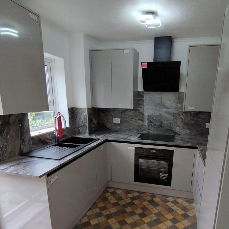 Compact laminate worktops Modern kitchen with grey cabinets, black appliances, and checkerboard tile flooring.
