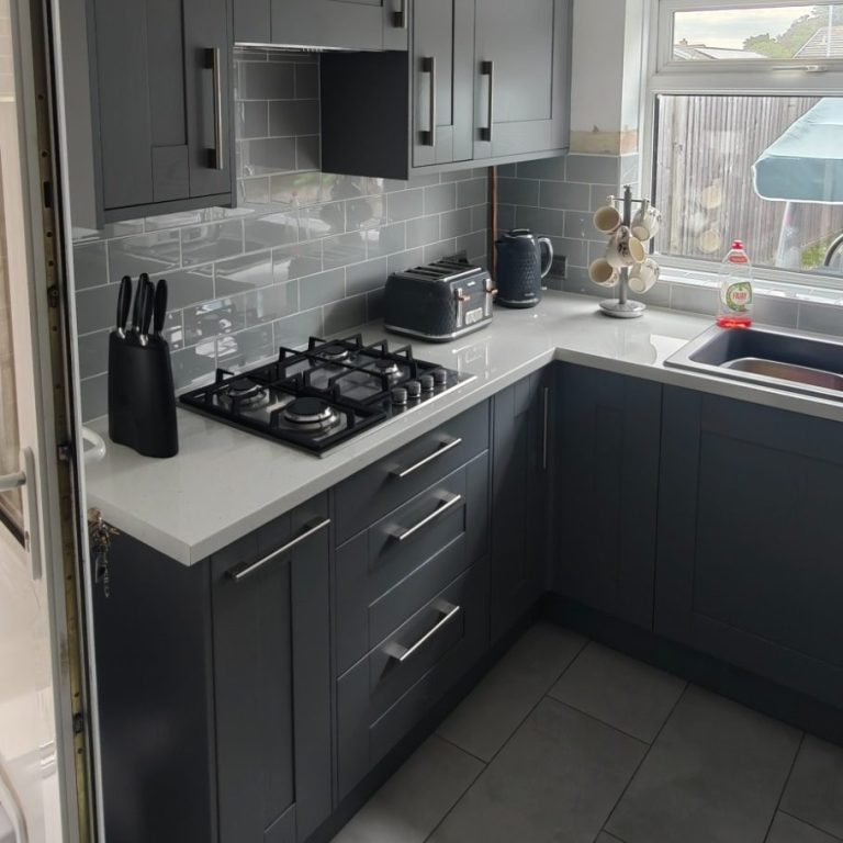 Grey kitchen Modern kitchen with grey cabinets, a gas stove, and a window letting in natural light.