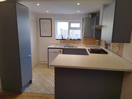 Modern kitchen with grey cabinets, a sink, and a stove, featuring a tile floor.