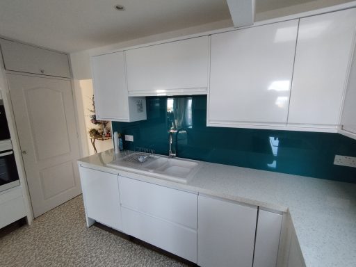 Modern kitchen with white cabinetry and a teal splashback.