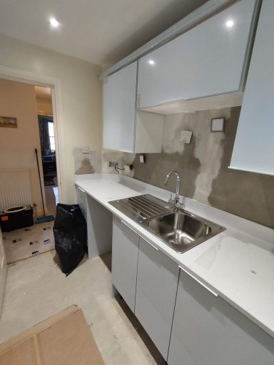 Modern kitchen with grey walls, white cabinets, and a stainless steel sink.