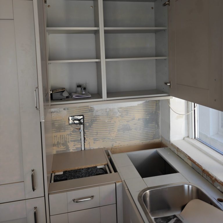 cabinets without worktops Modern kitchen with grey cabinetry, open shelves, and stainless steel sink.