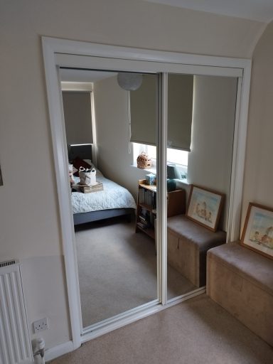 Interior view showing a mirrored wardrobe, bed, and furniture in a cozy room.