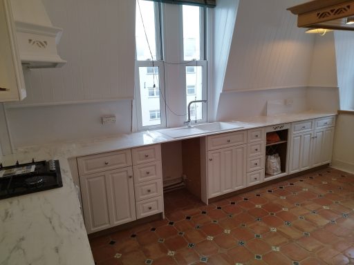Bright kitchen with white cabinets, marble countertops, and tiled flooring.