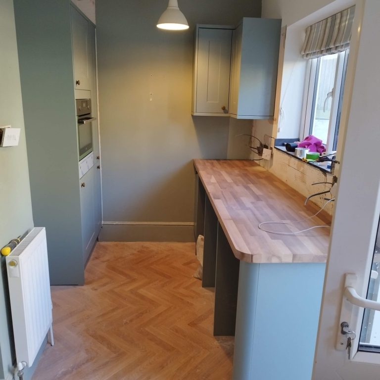 Howdens kitchen Modern kitchen with a wooden countertop and sage green cabinets
