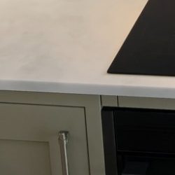 Worktop A marble kitchen countertop with a black cooktop and cabinet edge.