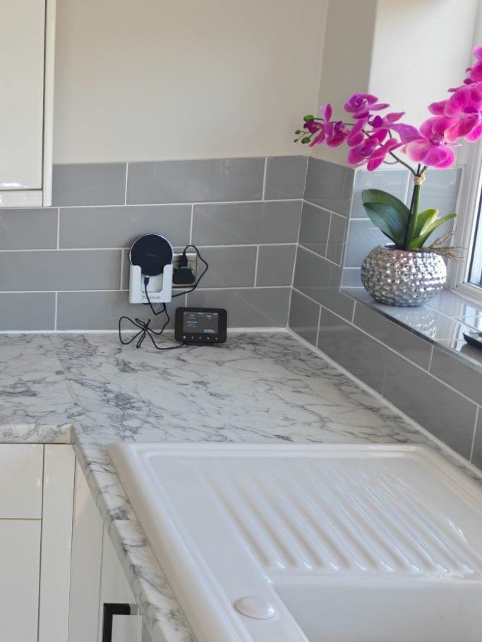 worktop and tiles Kitchen countertop with grey tiles, a clock, and a potted pink orchid.