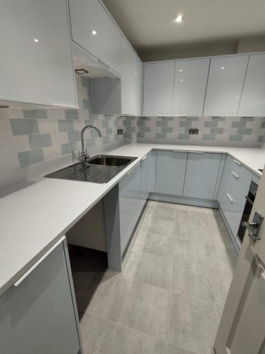 Modern kitchen with light blue cabinets, white countertops, and tiled backsplash.