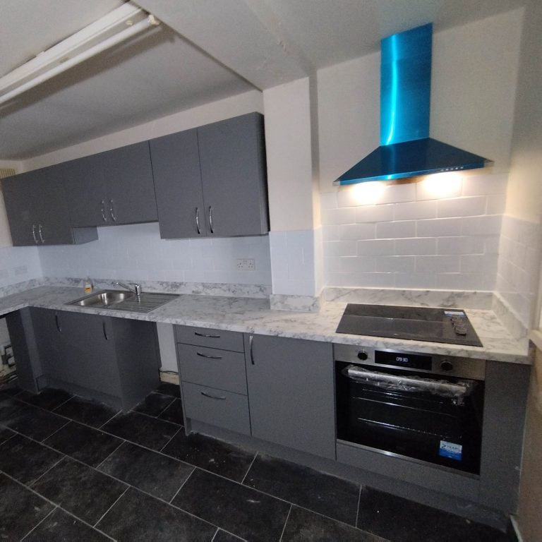 Bespoke grey kitchen Modern kitchen with grey cabinets, marble countertops, and a blue extractor hood.