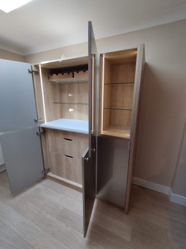 A modern wooden cupboard with open doors, featuring shelves and a countertop.